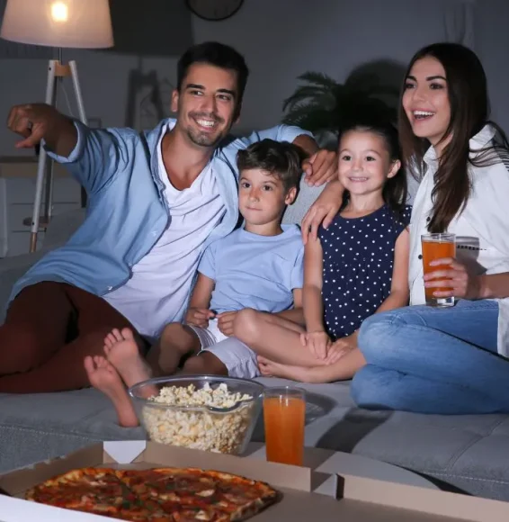 Famille heureuse regardant IPTV en Suisse Famille suisse réunie regardant la télévision avec passion, profitant de l’abonnement IPTV 4K